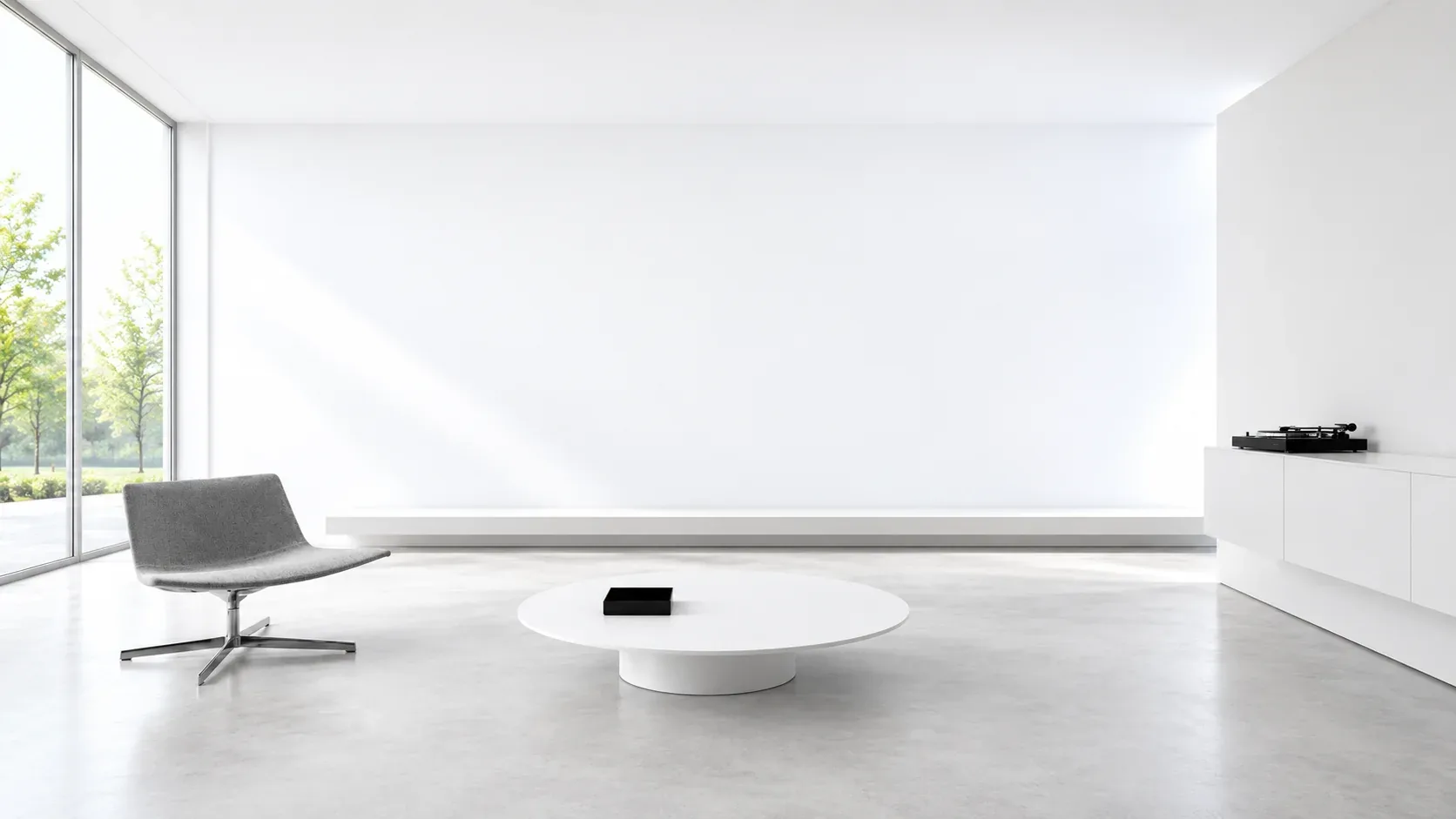 A white room with a low shelf along the wall, a grey chair and a record player.