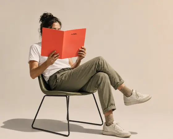 A person settled in a chair with the booklet open.