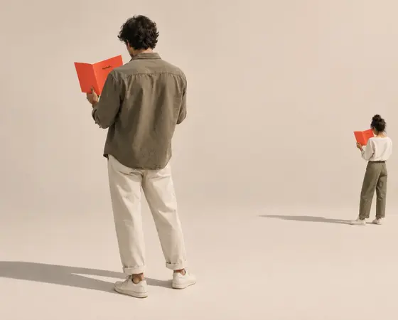 Two people standing apart, each reading the same red booklet.